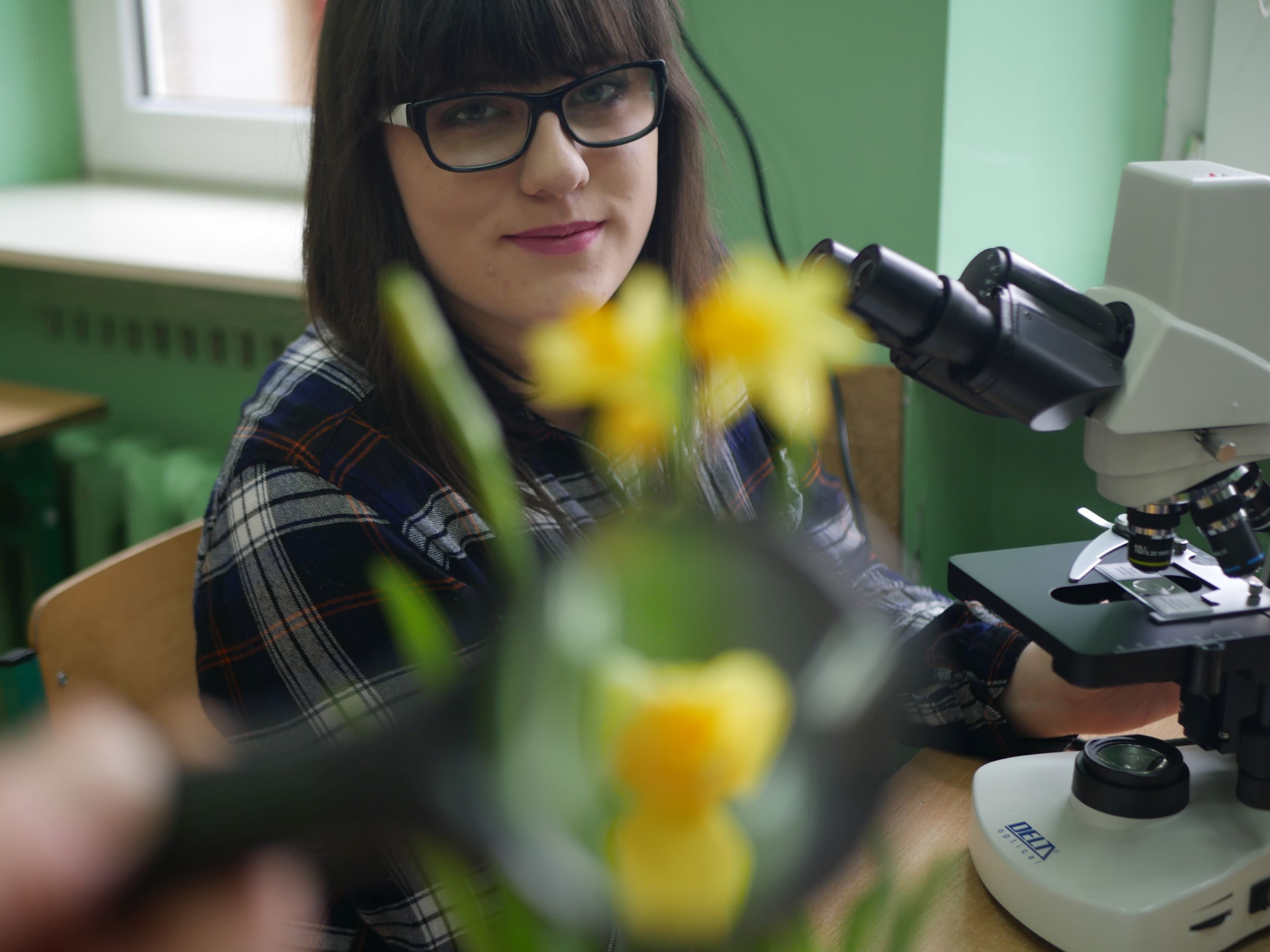 Zajęcia rozwijające zainteresowania z biologii, dziewczyna przy mikroskopie.
