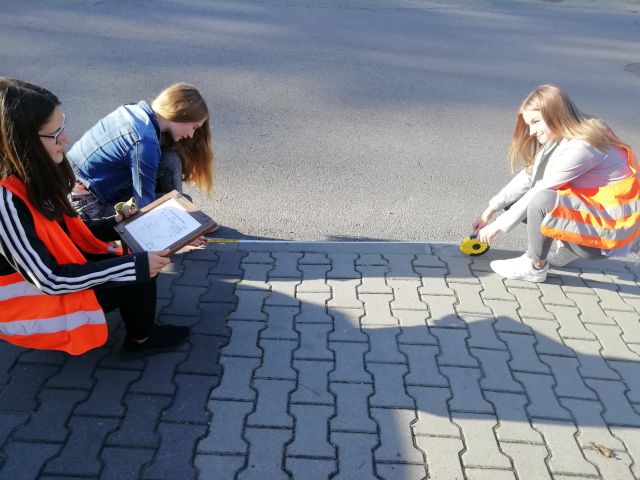 uczniowe miarką dokonują pomiaru kawałka ulicy