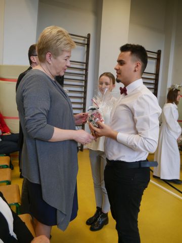 Uczeń składa życzenia i wręcza prezent nauczycielce.