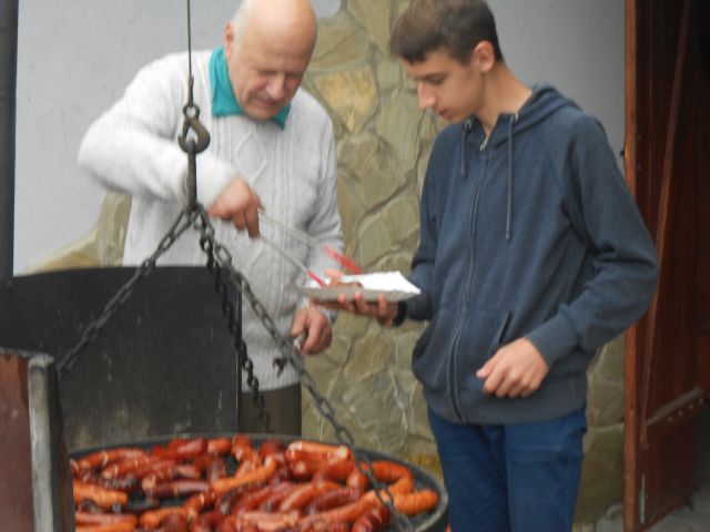 Starszy Pan nakłądający uczestnikowi kiełbasę z grilla