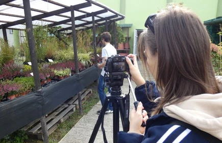 Dziewczyna fotografuje pracownika firmy Agrotechnik w trakcie wykonywania swoich obowiązków.