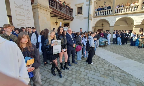 Uczniowie z kierownikiem warsztat&oacute;w na dziedzińcu zamku w NIepołomicach