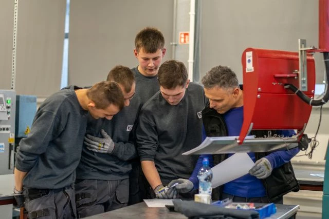 Pracownicy firmy Bohle (absolwenci ZS2 oraz starszy mężczyzna) podczas prac koncepcyjnych, pochyleni nad kartką papieru.